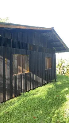 a black building with two windows in the grass at Cabañas con camping con tiendas de campaña Isla brava in Colorado