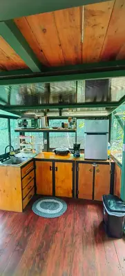 a kitchen with wooden cabinets and a stove top oven at Glamping Butterflay Garden in Concepción
