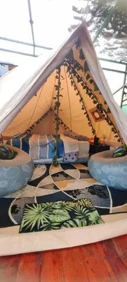a tent with pillows on a rug on a wooden floor at Glamping Butterflay Garden in Concepción