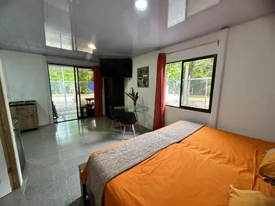 a bedroom with an orange bed and a table at ApartCasa Full Budget Apart House near beach and rain forest in Uvita