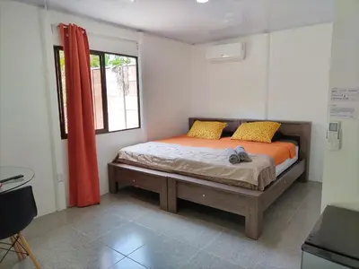 a bedroom with a bed with orange sheets and a window at ApartCasa Full Budget Apart House near beach and rain forest in Uvita