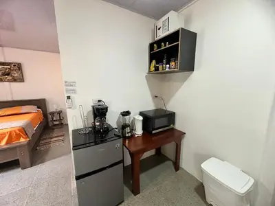 a room with a bed and a kitchen with a microwave at ApartCasa Full Budget Apart House near beach and rain forest in Uvita