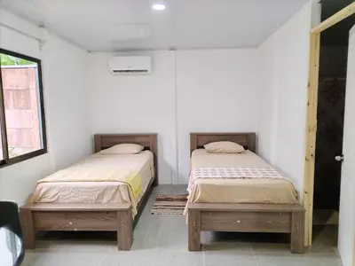 two twin beds in a room with white walls at ApartCasa Full Budget Apart House near beach and rain forest in Uvita