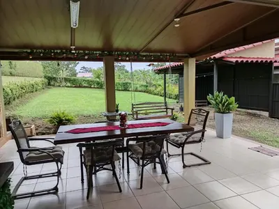 a patio with a table and chairs and a bench at Arenal Dreams House in Fortuna