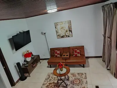 a living room with a couch and a tv at Arenal Dreams House in Fortuna