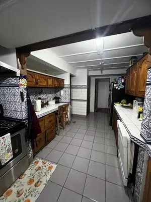a large kitchen with wooden cabinets and a tile floor at Casa Aldaba in San José