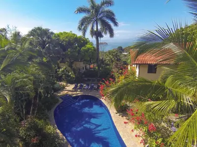 an aerial view of a resort swimming pool with palm trees at Hotel Villas Nicolas - Adults Only in Manuel Antonio