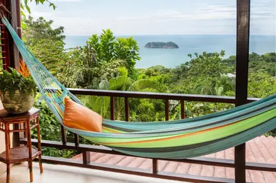 a hammock on a balcony with a view of the ocean at Hotel Villas Nicolas - Adults Only in Manuel Antonio