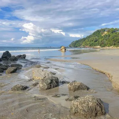 a beach with rocks and people in the water at Hotel Villas Nicolas - Adults Only in Manuel Antonio