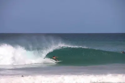 a man riding a wave on a surfboard in the ocean at Hotelito Dos Hijas Casita 3 in Refundores