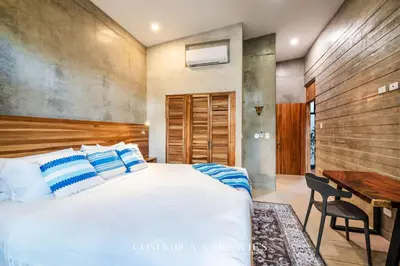 a bedroom with a large bed and a desk at Steps to the Main Surf Break - 3 Bedroom House in Refundores