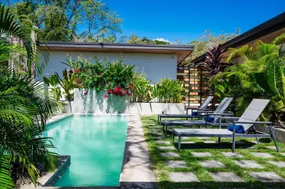 a swimming pool with lounge chairs next to a house at Villa Serenity 6 bedroom - 1 minute to the beach in Santa Cruz