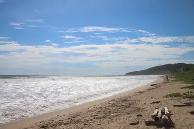 a beach with the ocean and people in the water at Villa Serenity 6 bedroom - 1 minute to the beach in Santa Cruz