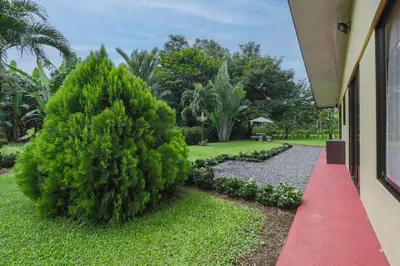 a red path in front of a house with a bush at La Casa Amarilla in Fortuna