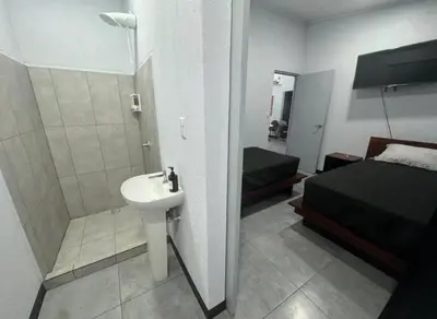 a bathroom with a sink and a bedroom with a bed at Casa Tusi - 2 Blocks From Clubs & Strip in Jacó