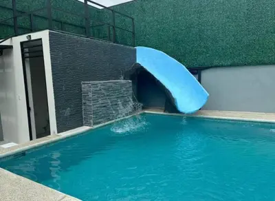 a blue water slide in a swimming pool at Casa Tusi - 2 Blocks From Clubs & Strip in Jacó