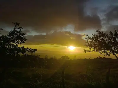 a sunset in a field with the sun setting at Monte Green Villa Romántica con jacuzzi in Monteverde Costa Rica