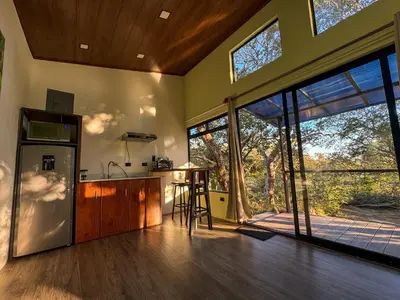 a kitchen with a refrigerator and a table in a room at Monte Green Villa Romántica con jacuzzi in Monteverde Costa Rica