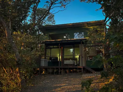 a glass house in the woods at night at Monte Green Villa Romántica con jacuzzi in Monteverde Costa Rica