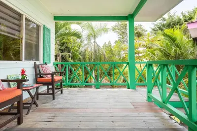 a green porch with benches and chairs on it at #28 Beach Bungalow in Playa Hermosa