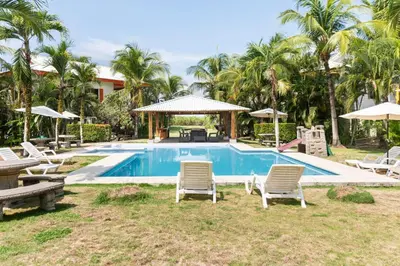 a swimming pool with chairs and a table and umbrella at #28 Beach Bungalow in Playa Hermosa
