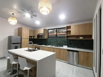 a kitchen with a white counter top and wooden cabinets at Casa Pacifica in Uvita