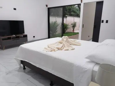a white bed in a room with a tv at Casa Pacifica in Uvita