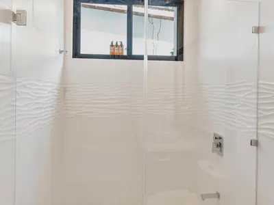 a glass shower in a bathroom with a window at Surfside Apartments - Playa Mar Azul in Mal País