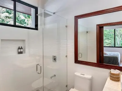 a bathroom with a shower and a toilet and a mirror at Surfside Apartments - Playa Mar Azul in Mal País