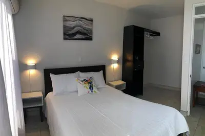 a bedroom with a large white bed with two lamps at Plaza Avenida Uno in Puntarenas