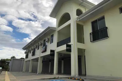 a large white building with windows and a sky at Plaza Avenida Uno in Puntarenas