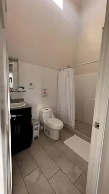 a white bathroom with a toilet and a shower at Plaza Avenida Uno in Puntarenas