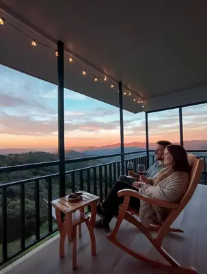 a man and woman sitting on a balcony with a glass of wine at Nosara Hideaway 3 - BREAKFAST PROVIDED & Mountain View Cabins in Nosara