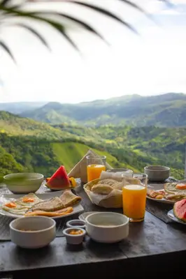 a table with plates of food and glasses of orange juice at Nosara Hideaway 3 - BREAKFAST PROVIDED & Mountain View Cabins in Nosara