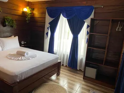 a bedroom with a bed with blue curtains and a window at Sol y Luna Chalet in Fortuna