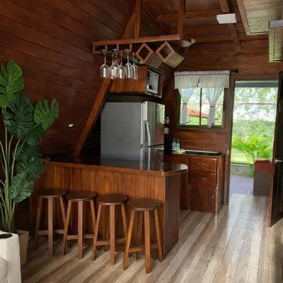 a kitchen with wooden walls and a counter with stools at Sol y Luna Chalet in Fortuna