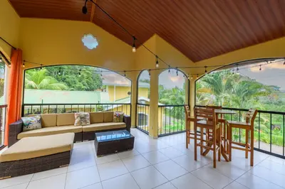 a living room with a couch and a table on a balcony at Jungle & Beach Retreat Villa Tranquilo in Esterillos Este