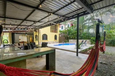 a hammock in front of a house with a pool at Jungle & Beach Retreat Villa Tranquilo in Esterillos Este
