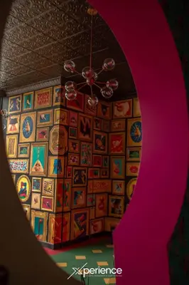 a room with a ceiling fan and a wall of paintings at Firefly at 29, City Views and Wonderland Vibes! in Hatillo