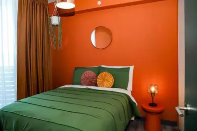 a bedroom with a green bed with an orange wall at Bloum at 22, City Views and Wonderland Vibes! in Hatillo