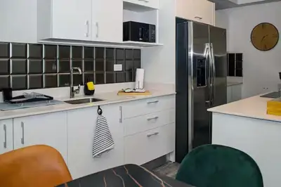 a kitchen with white cabinets and a stainless steel refrigerator at Bloum at 22, City Views and Wonderland Vibes! in Hatillo