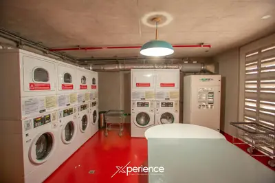 a laundry room with three washer and dryer machines at Grotto at 28, City Views and Wonderland Vibes! in Hatillo