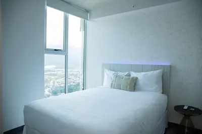 a white bed in a room with a large window at Blue Nun at 29, City Views and Wonderland Vibes! in Hatillo