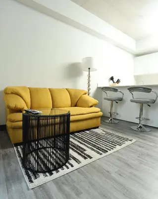 a living room with a yellow couch and two stools at Sunflower at 12, City Views and Wonderland Vibes! in Hatillo