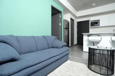 a living room with a blue couch and a kitchen at Teal at 12, City Views and Wonderland Vibes! in Hatillo