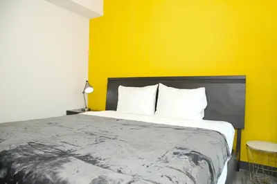 a bedroom with a large bed with a yellow wall at Indigo at 11, City Views and Wonderland Vibes! in Hatillo