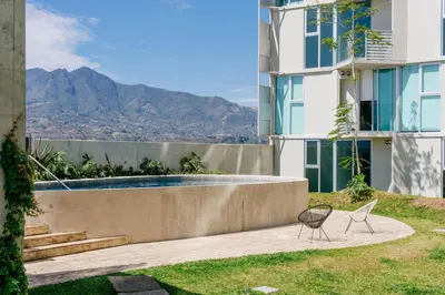a view of a building with a pool and a chair at Gold Rabbit at 26, City Views and Wonderland Vibes! in Hatillo
