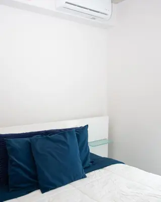 a bed with a white headboard and a blue pillow at Gold Rabbit at 26, City Views and Wonderland Vibes! in Hatillo