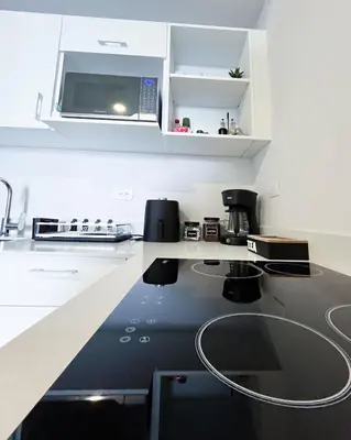 a kitchen with a microwave and a black counter top at Serenity at 12, City Views and Wonderland Vibes! in Hatillo