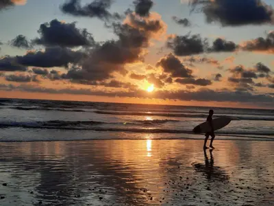 a man walking on the beach with a surfboard at Casa Mor - Surfhouse - 2 min from the beach in Santa Teresa Beach